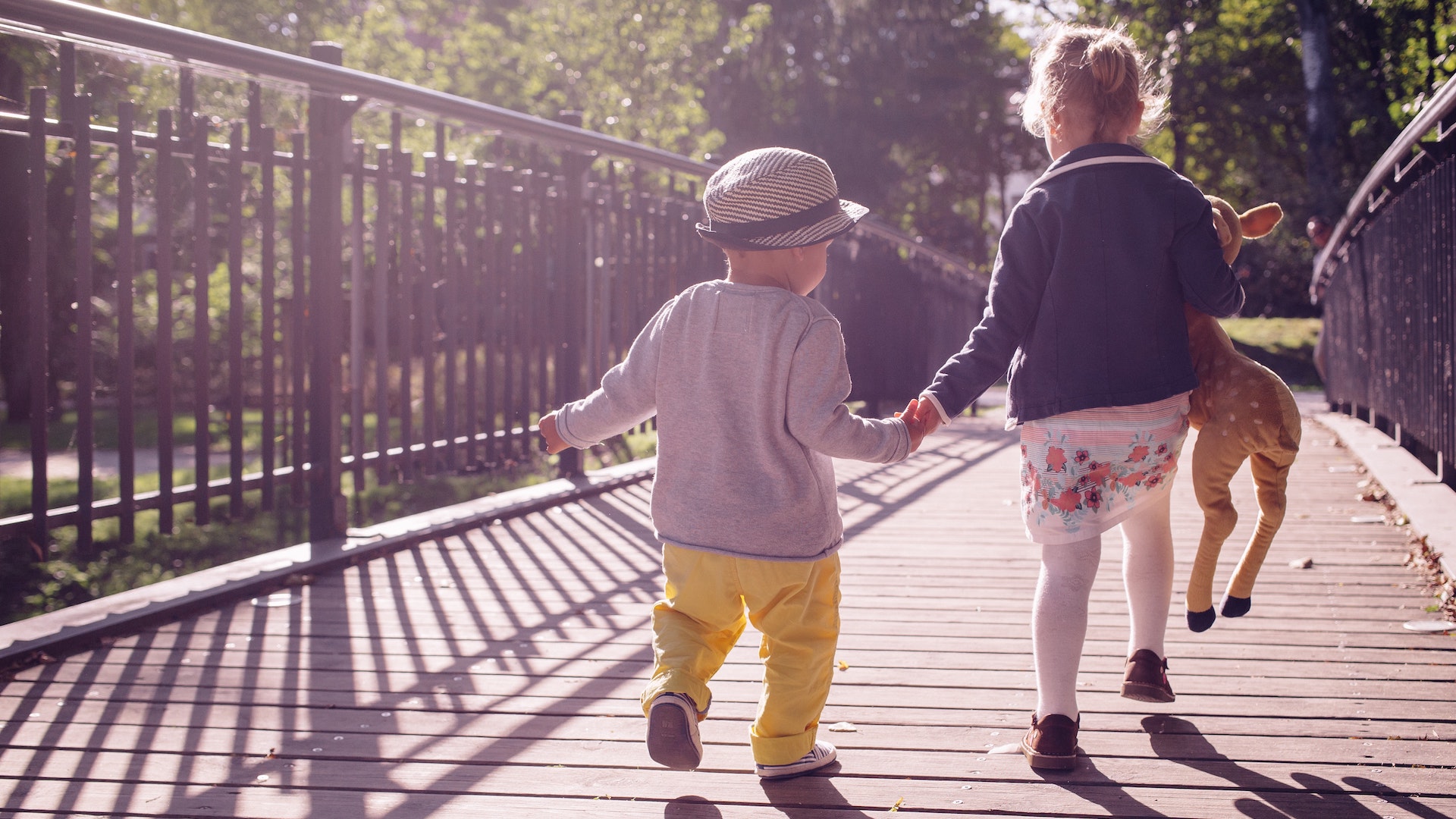 children play ho.ding hands on a bridge