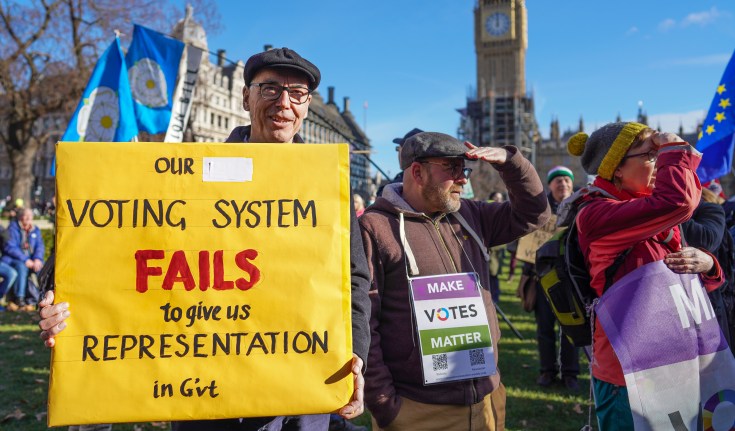 Campaigners at an electoral reform protest. One man is holding a sign reading: Our voting system fails to give us representation in government