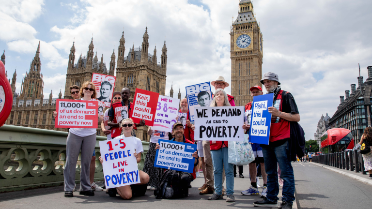 Big Issue vendors, frontline staff and campaigners with placards calling for an end to poverty on Westminster Bridge.