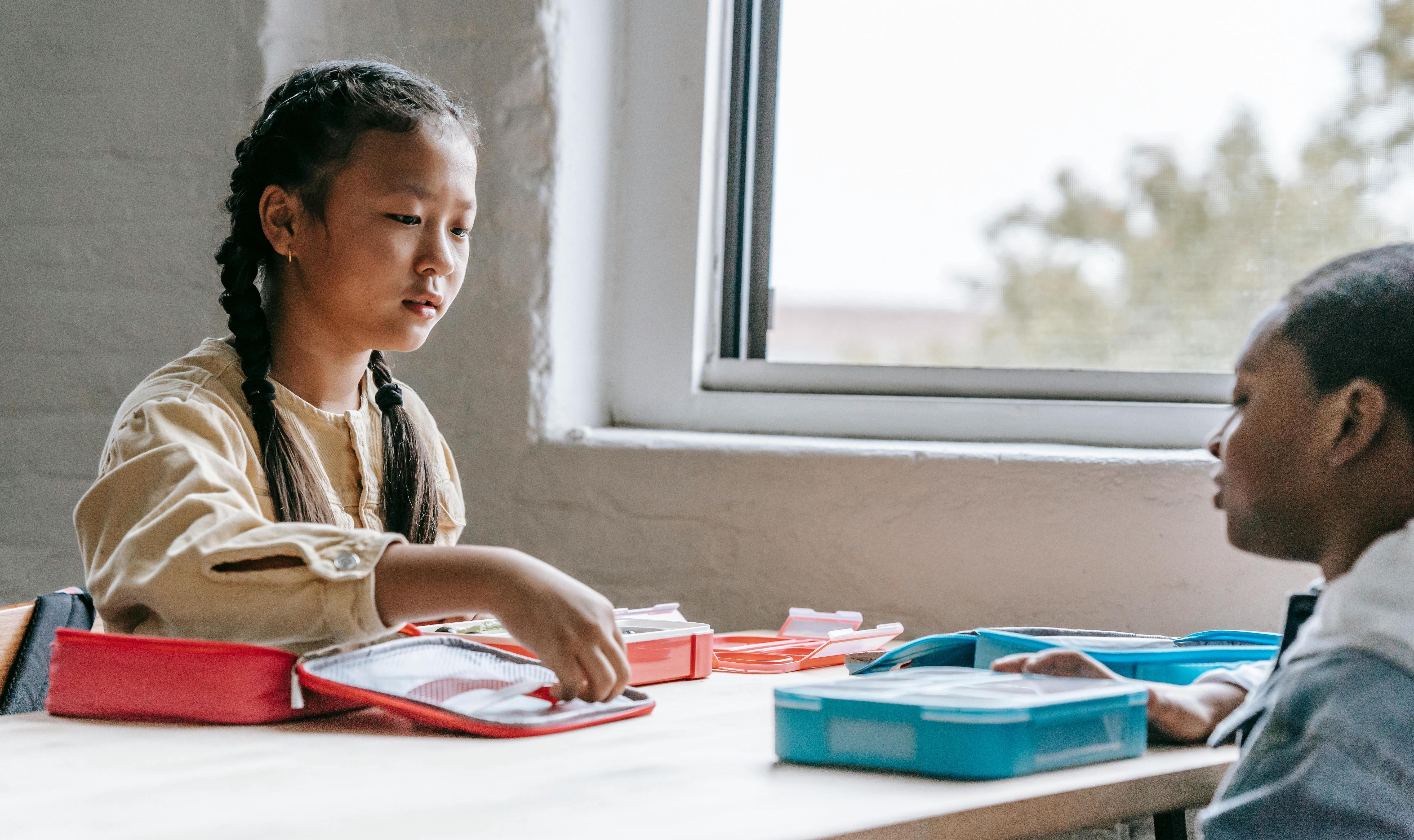 Stock image of children eating out of lunchboxes to illustrate an article about free school meals