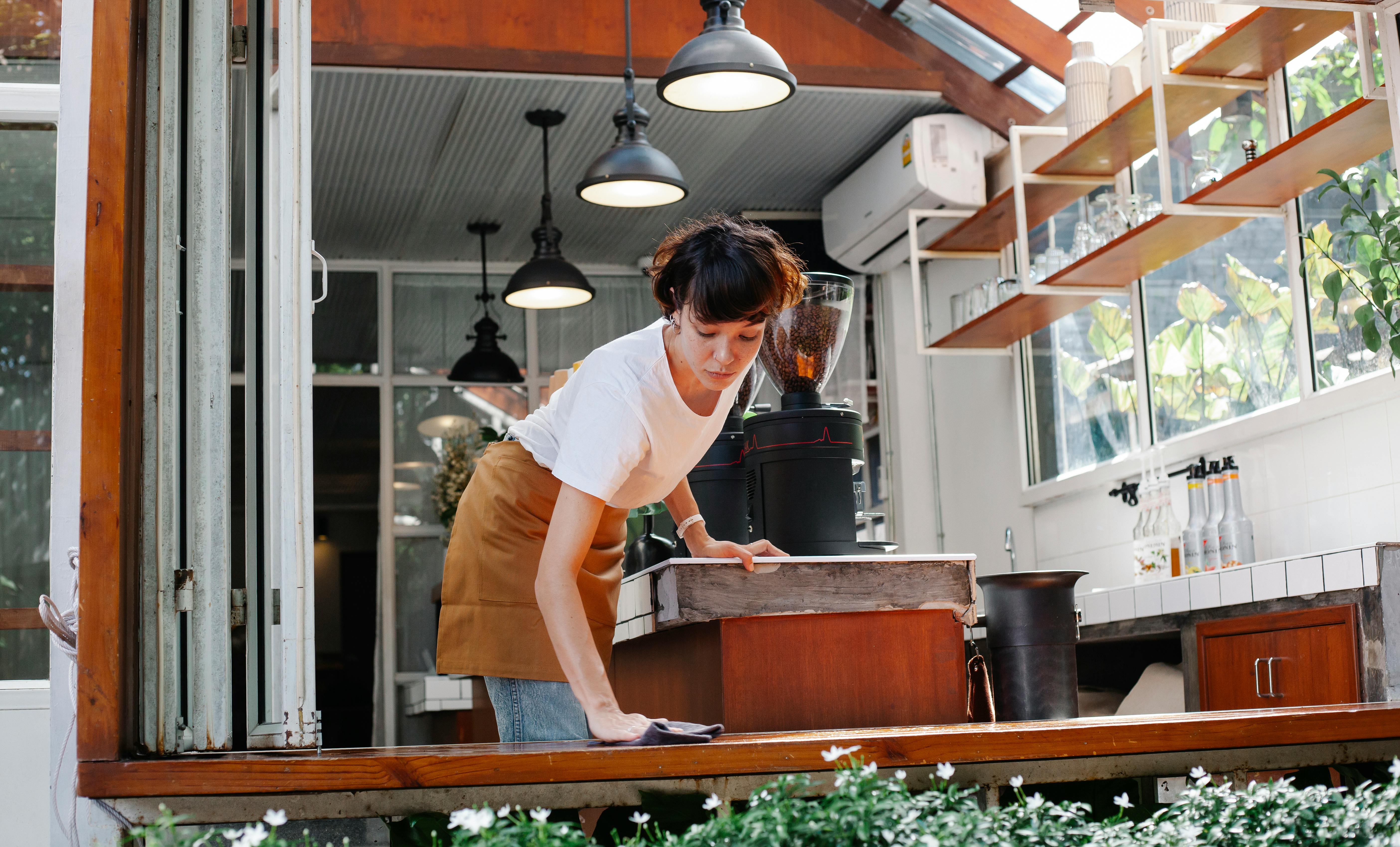 A young woman cleaning a table in a cafe