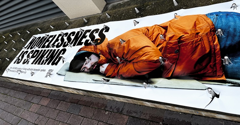 Poster of a homeless person pierced by spkes designed to deter rough sleepers, known as hostile architecture