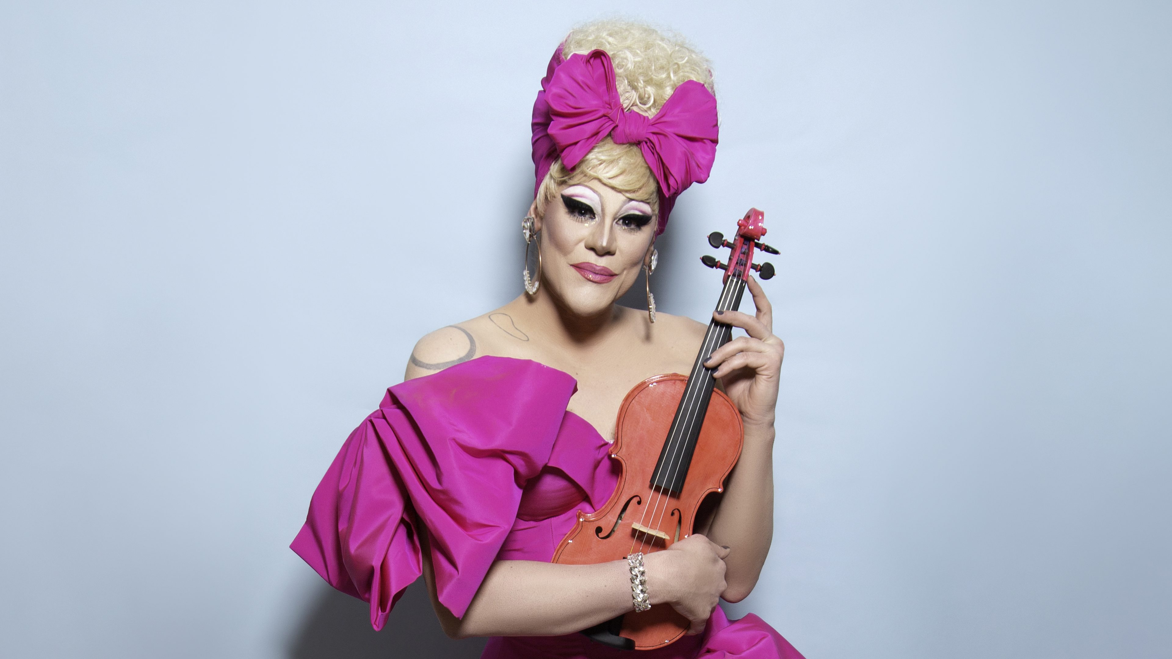 Star of RuPaul's Drag Race Thorgy Thor in a pink dress holding her violin