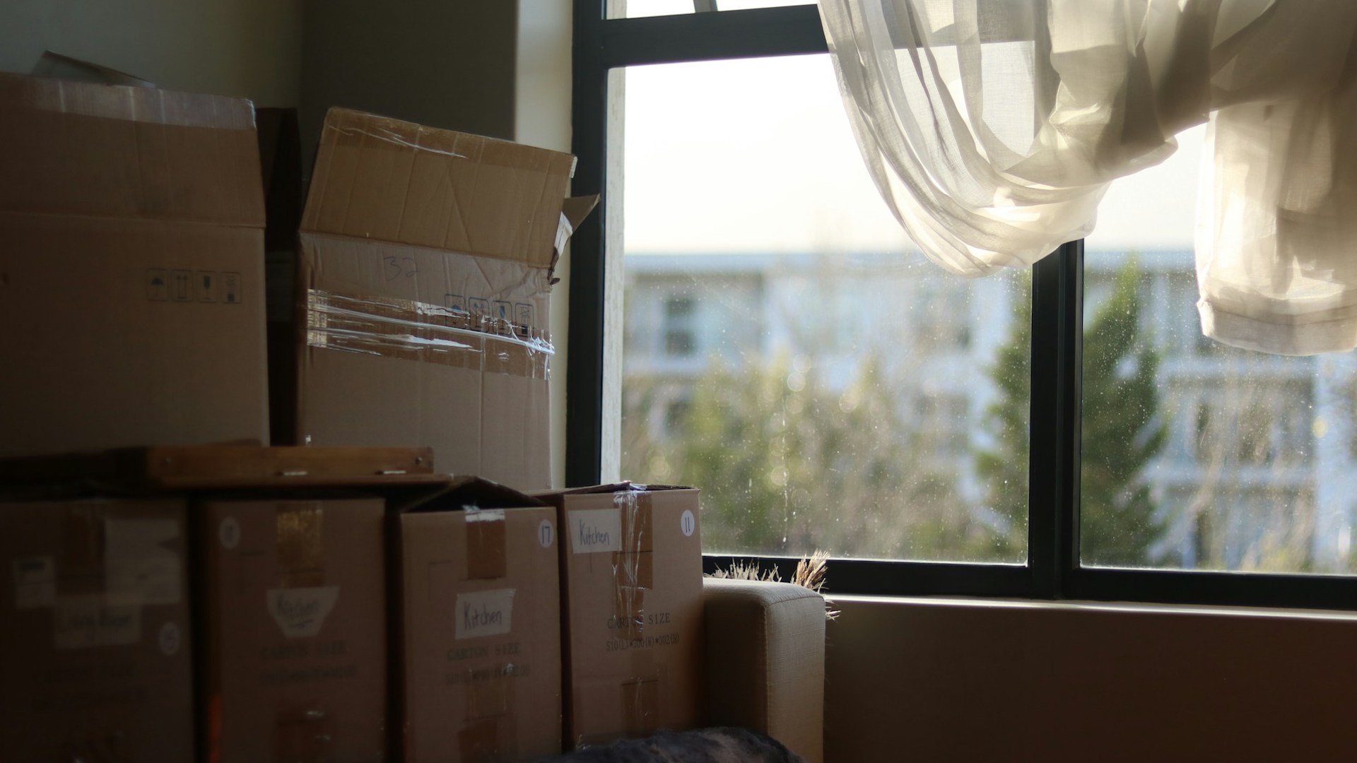 a pile of cardboard moving boxes in front of a window. ending a fixed term tenancy