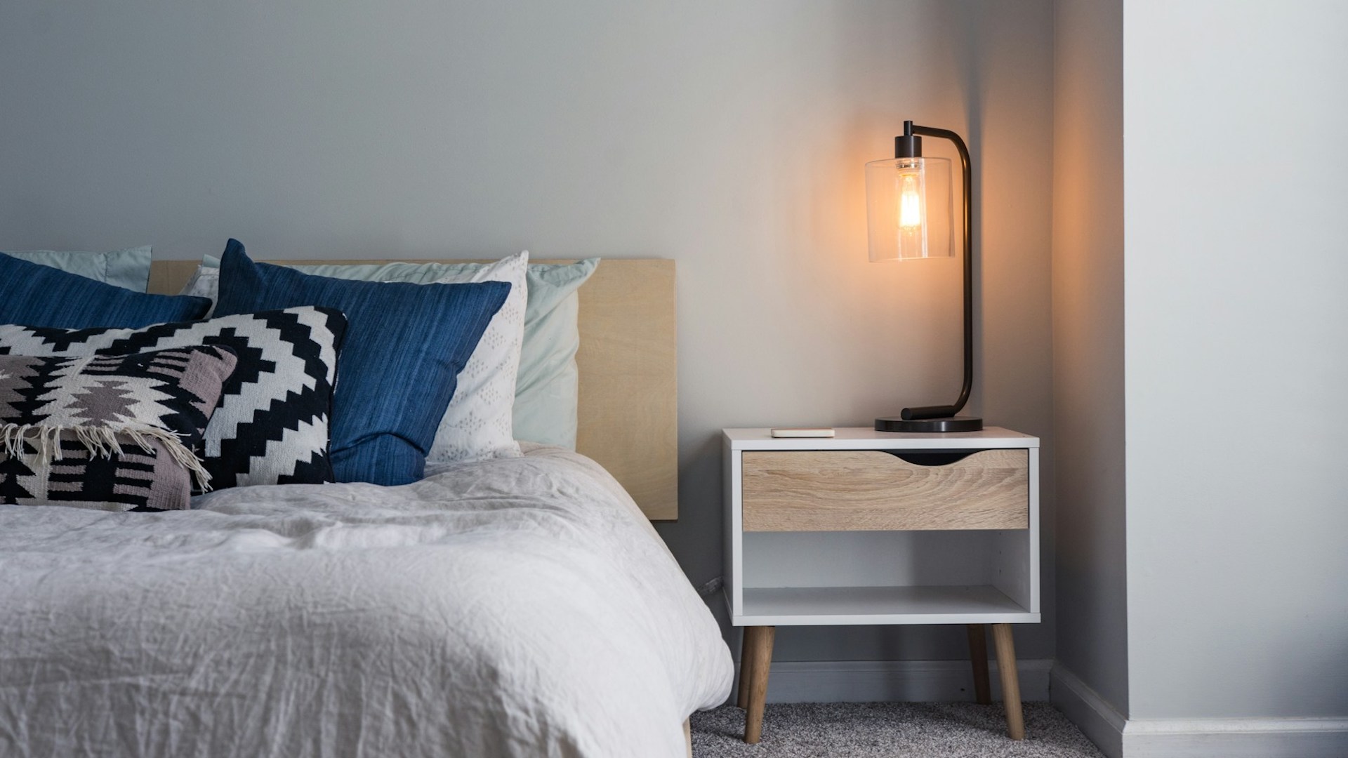 a bed in a bedroom with a bedside table and lamp. is subletting illegal?