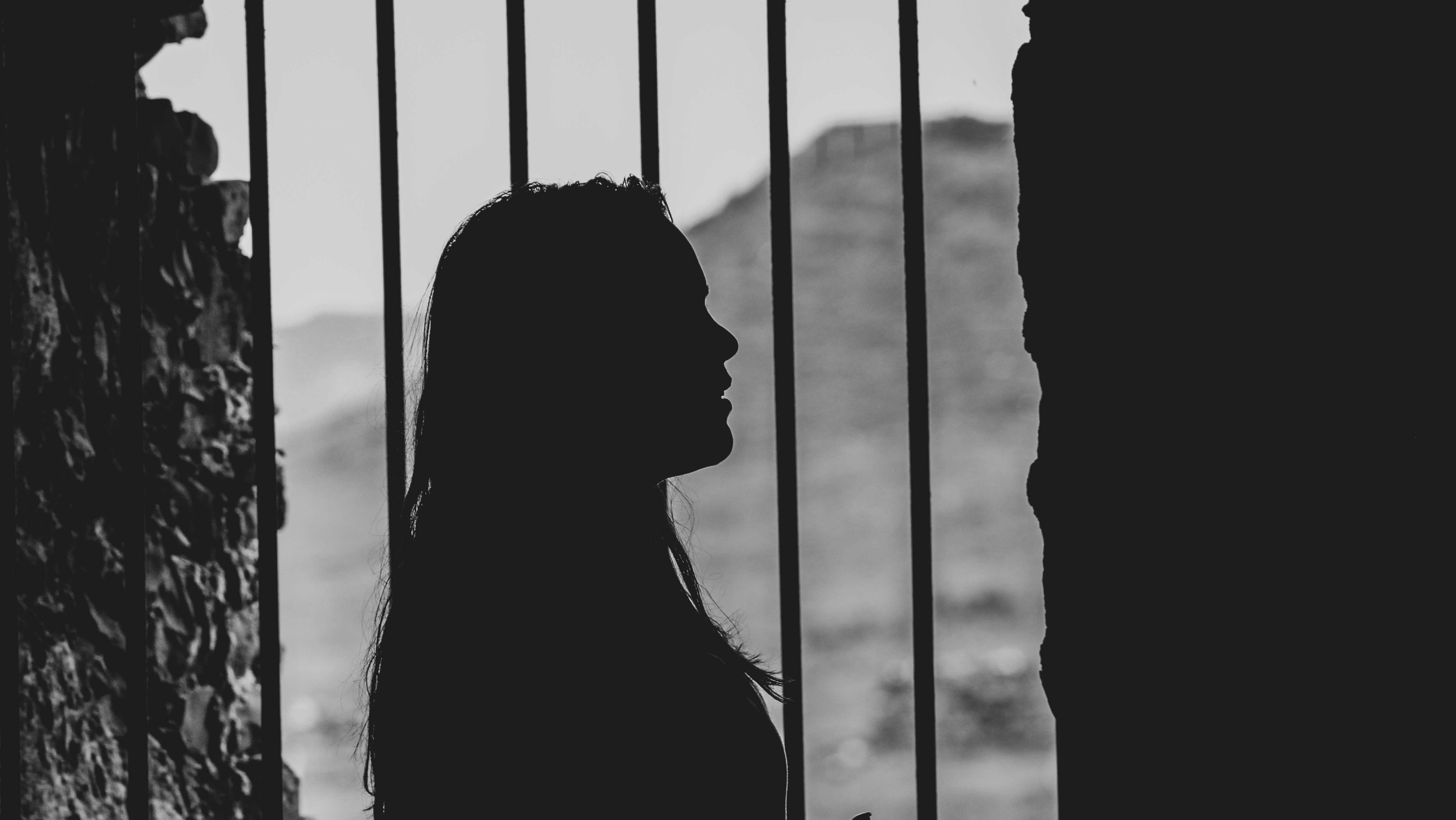 The silhouette of a women standing in front of prison bars