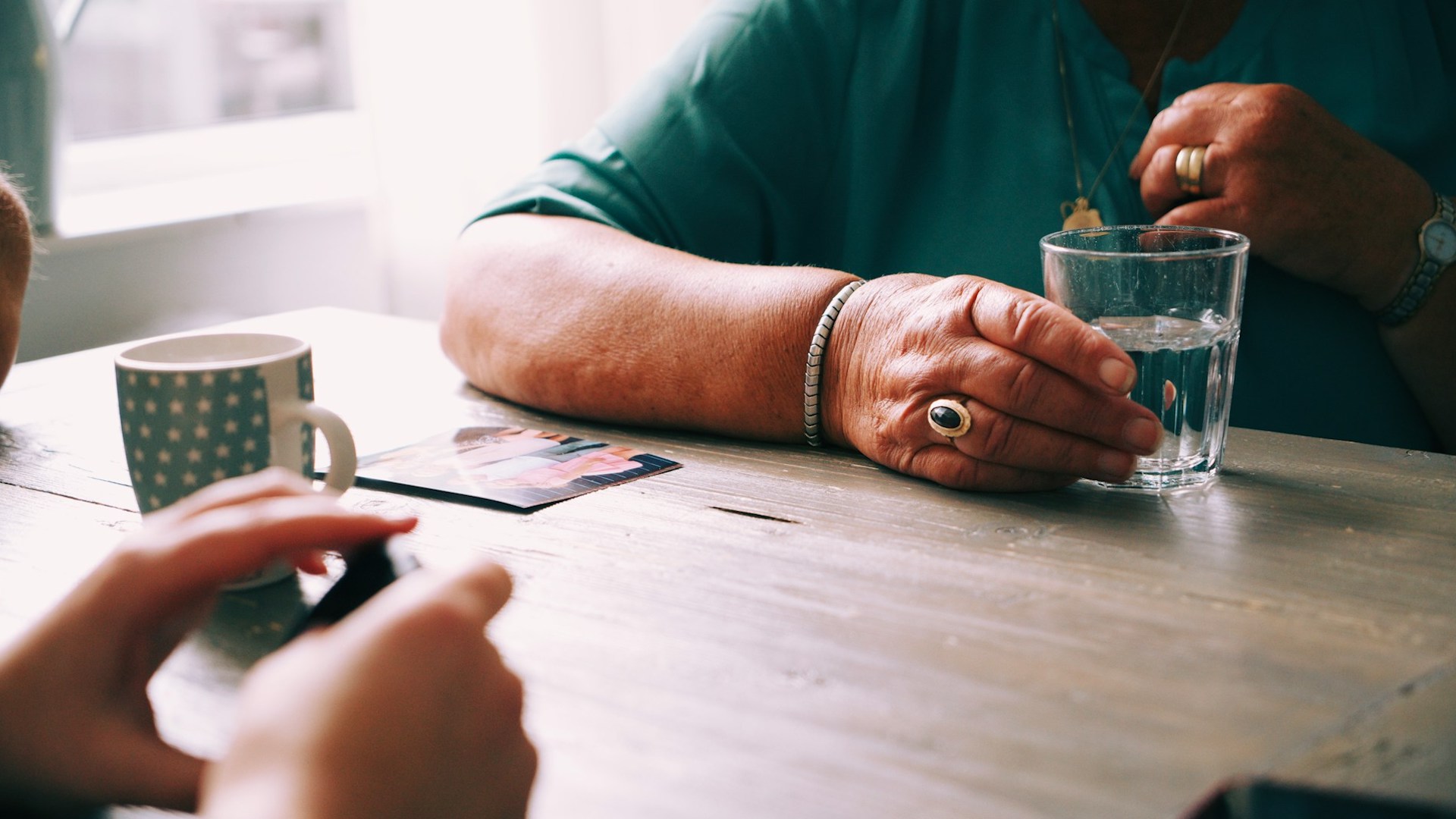 The arms of two people sat across a wooden table from each other. What is a guarantor for rent?