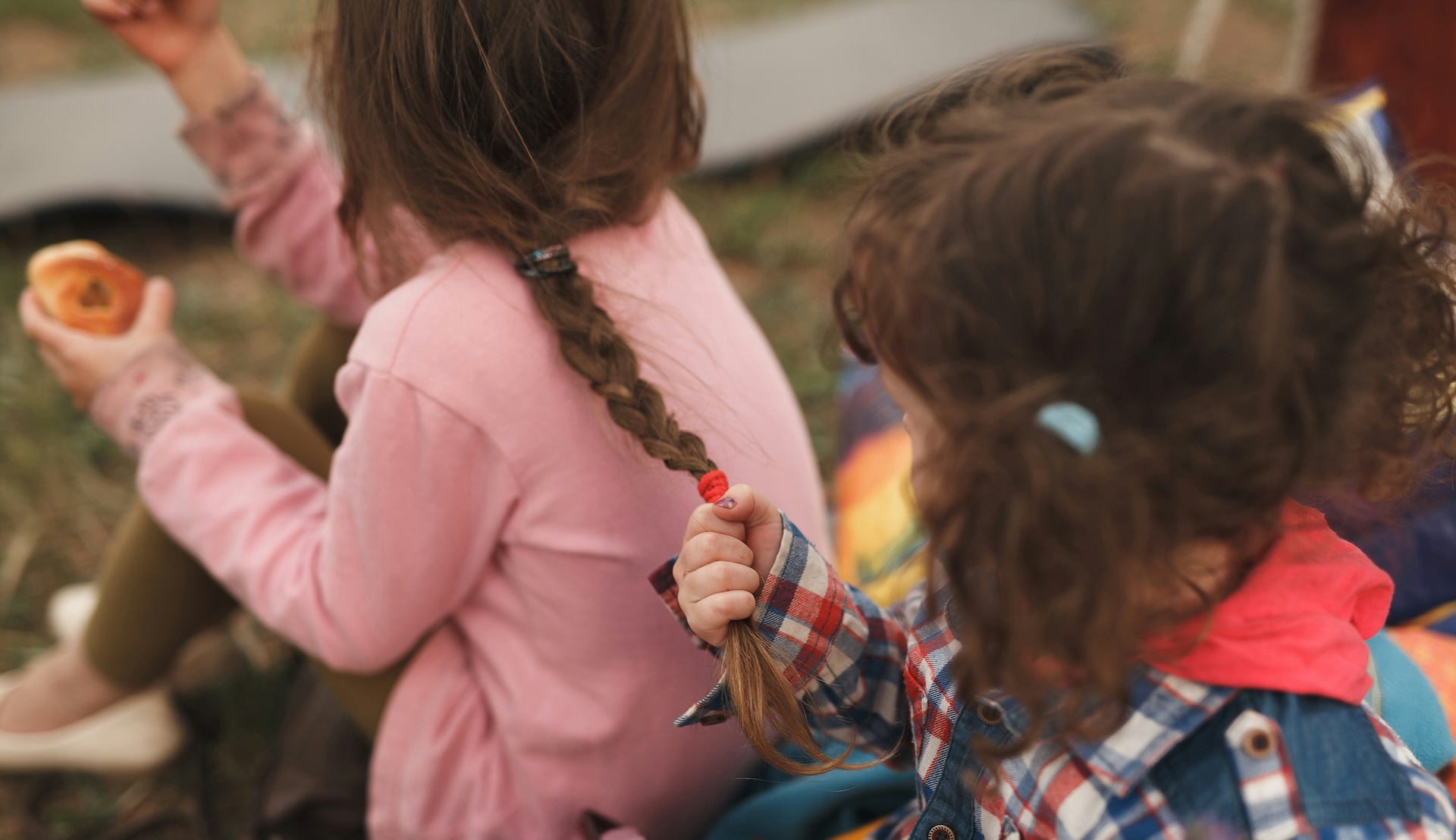 child pulling hair of another child who is eating