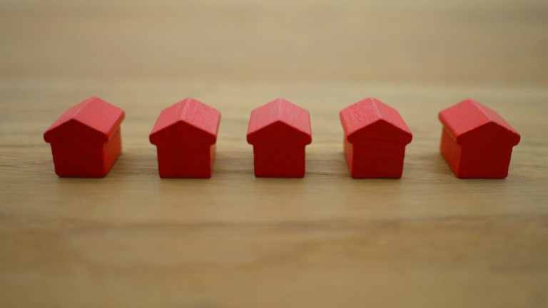 Six small red wooden houses in a row on a wooden surface. How much can a landlord increase rent?