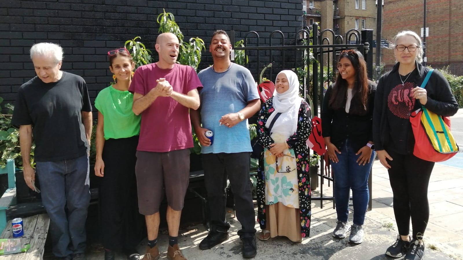 a group of people stands outside Shadwell Overground station in east London