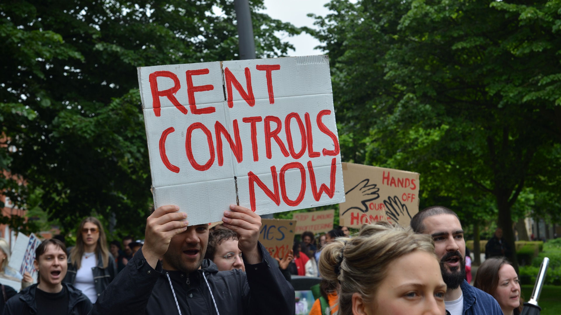 Activists from London Renters Union hold up placard calling for "Rent controls now".