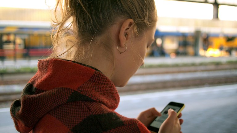 a woman using her phone on a train platform