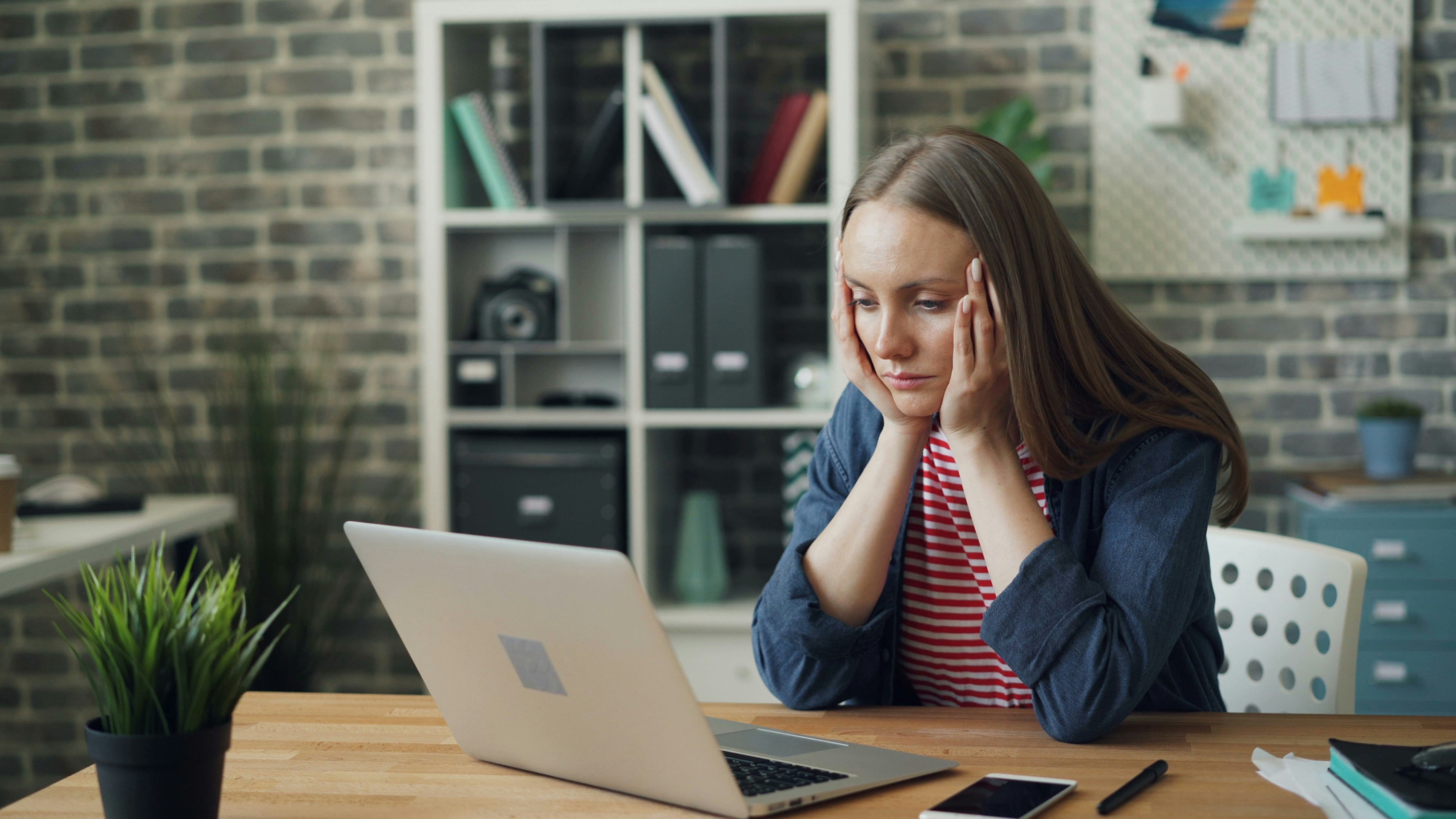 woman at laptop looking stressed