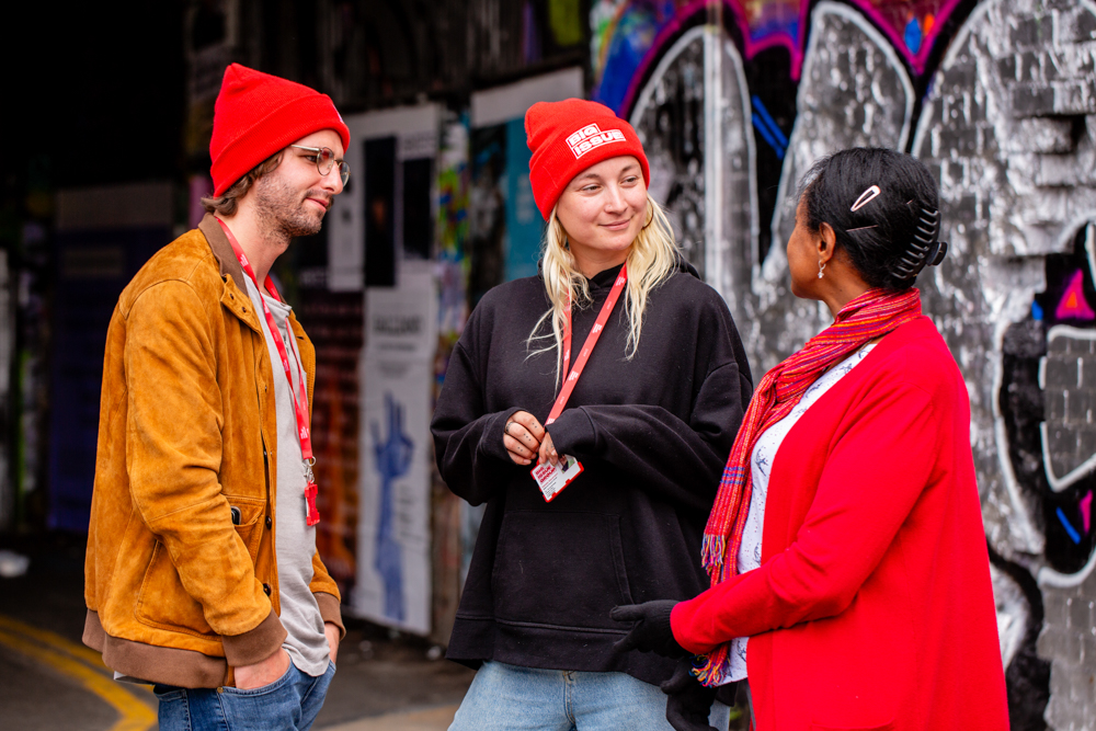 3 Big Issue support staff stand chatting