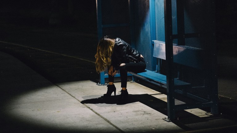 a woman in street light at bus stop