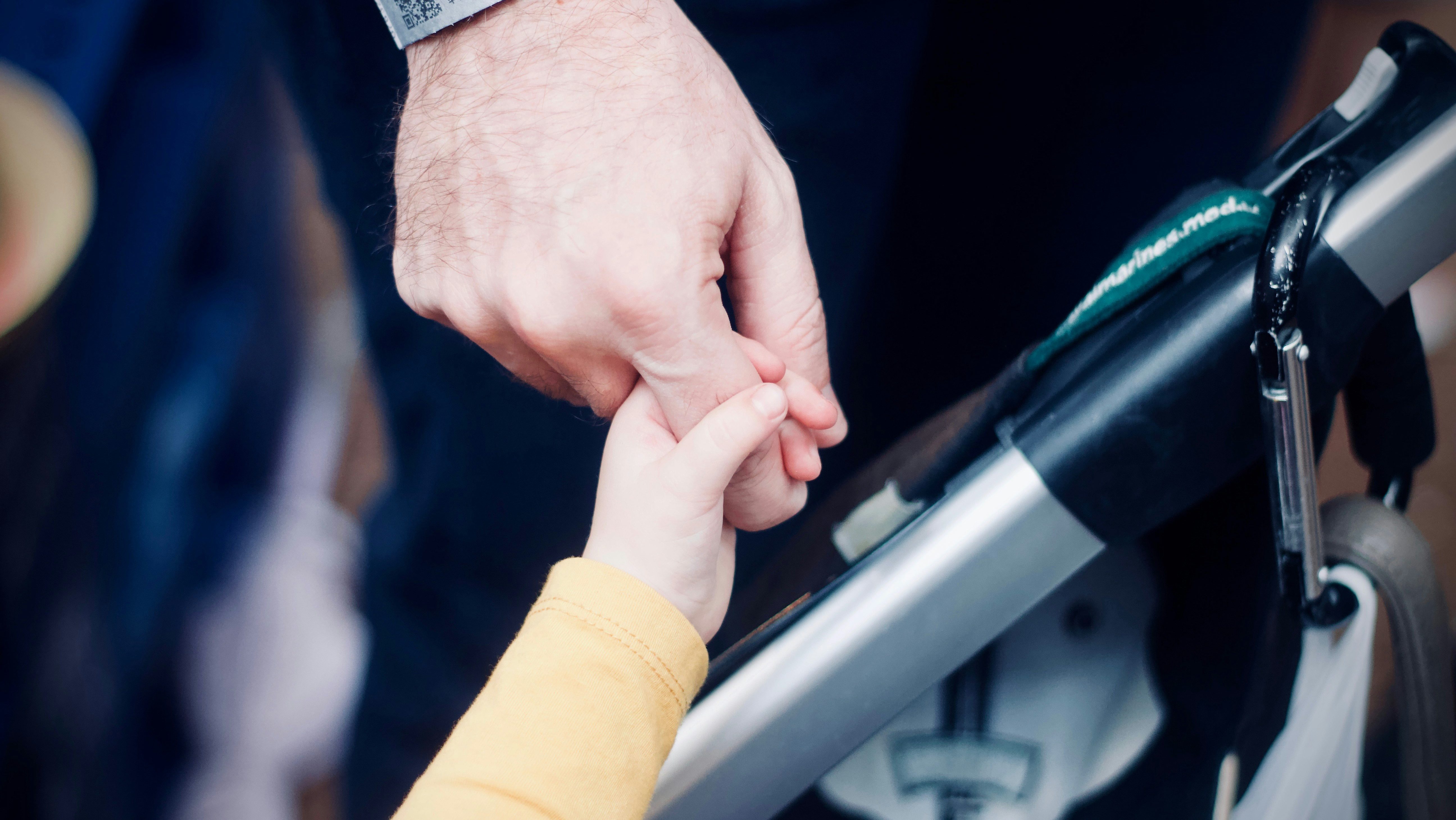 A small child's hand holds an adult's finger