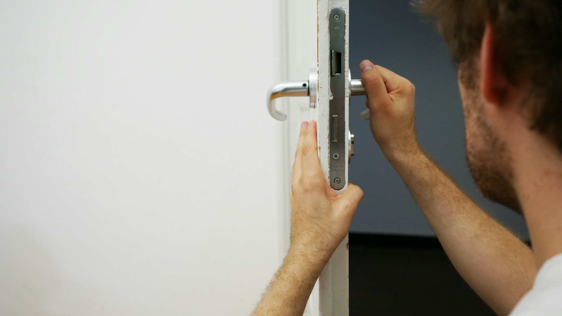 a man knelt down fixing the lock on a door