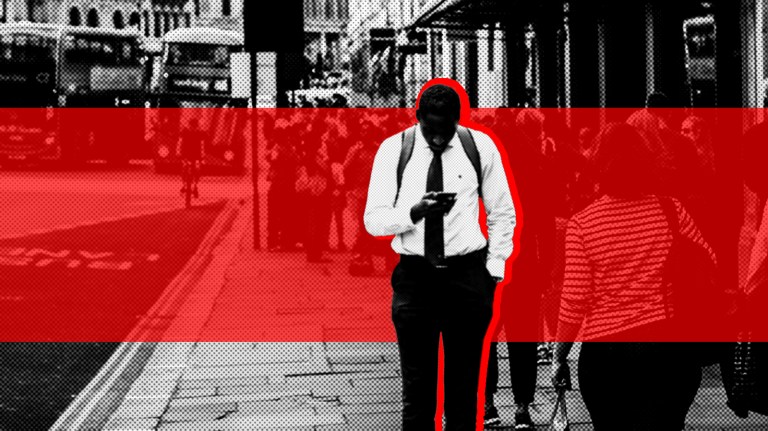 a man stands on a busy street in London and checks his phone