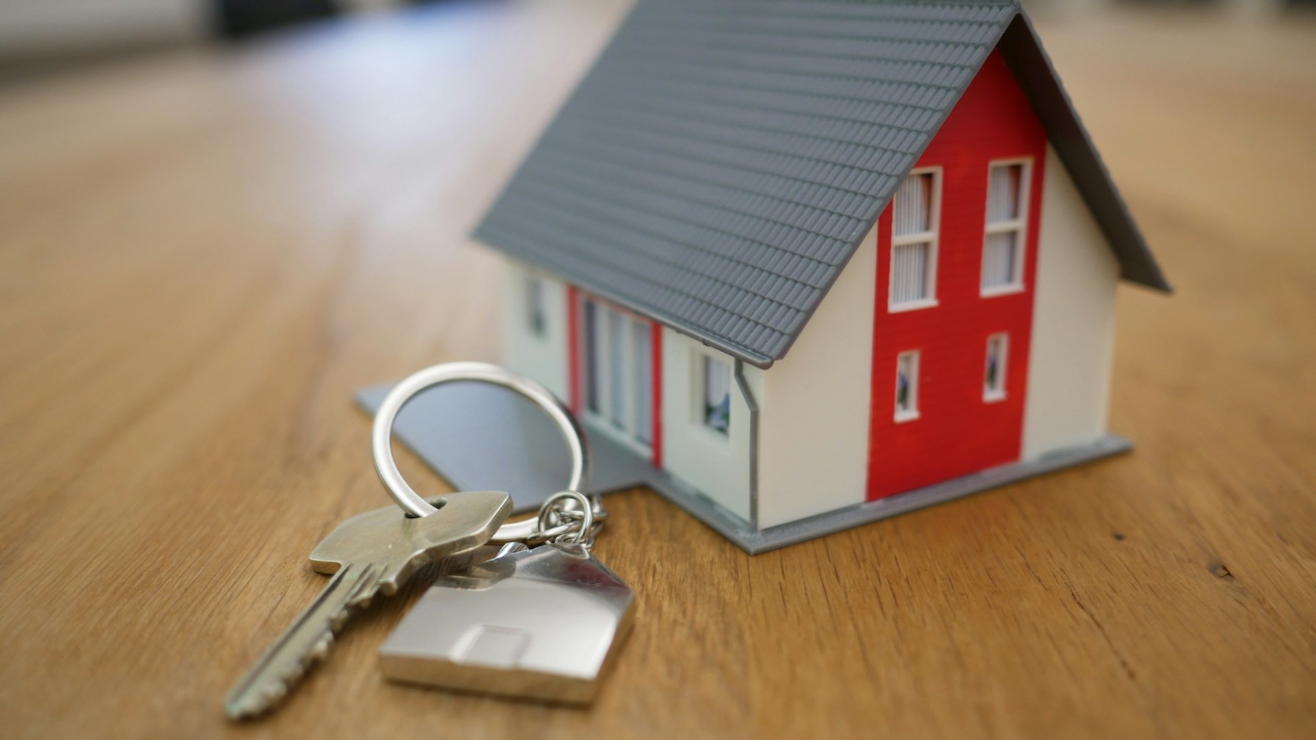 set of keys on a table attached to a keyring in the shape of a house