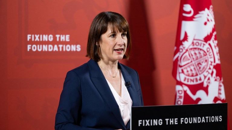 Rachel Reeves stands at a podium in front of a red background