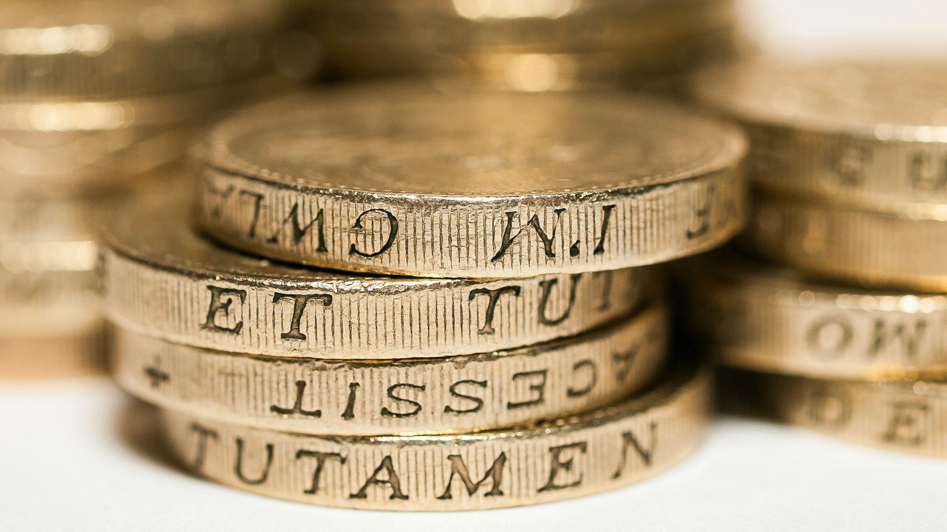 a pile of pound coins on a white surface // unemployment benefits