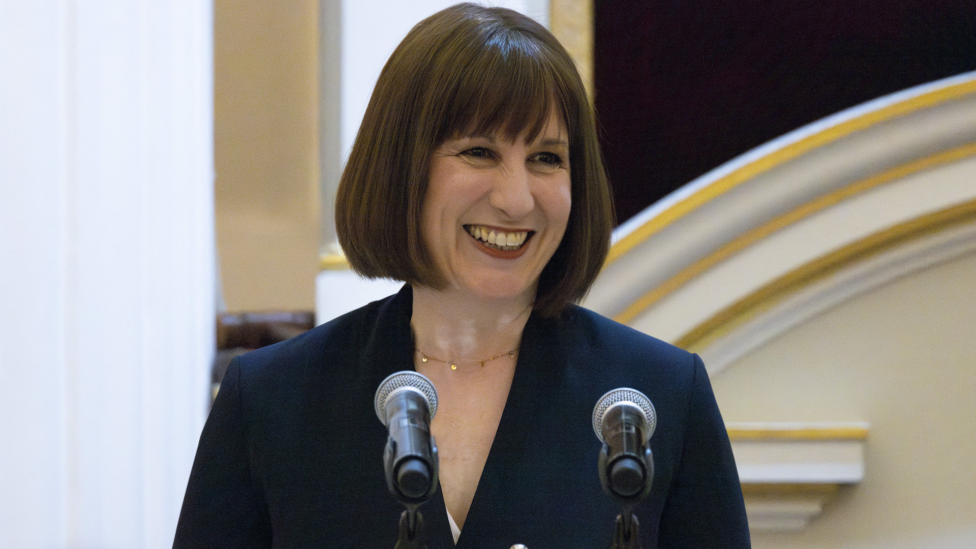 Chancellor Rachel Reeve standing at a podium and smiling