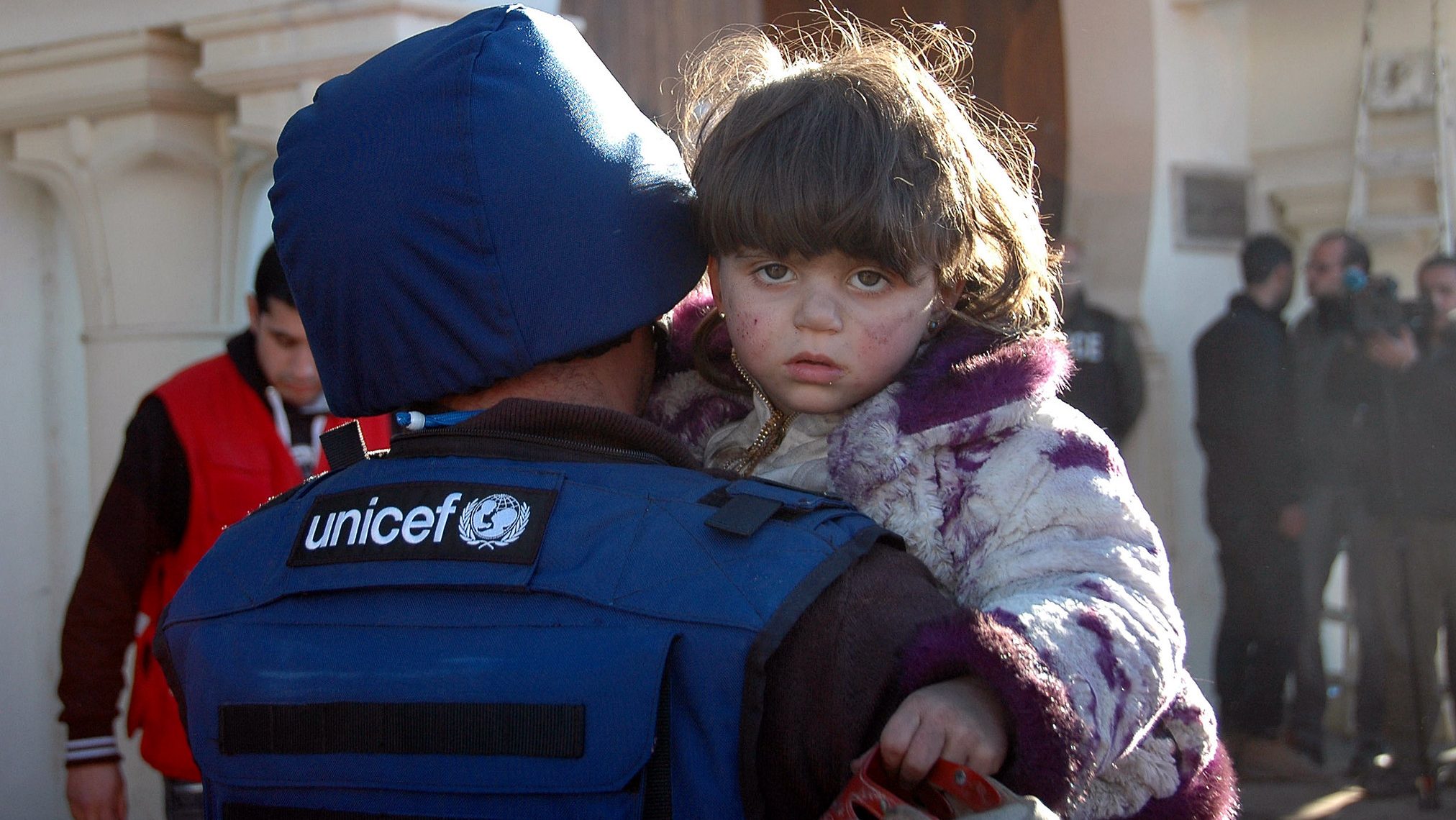 A UNICEF worker holds a child outside a shelter center in Homs, Syria