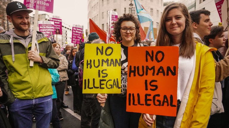 immigration and refugeee rights protestors hold up placards reading: 