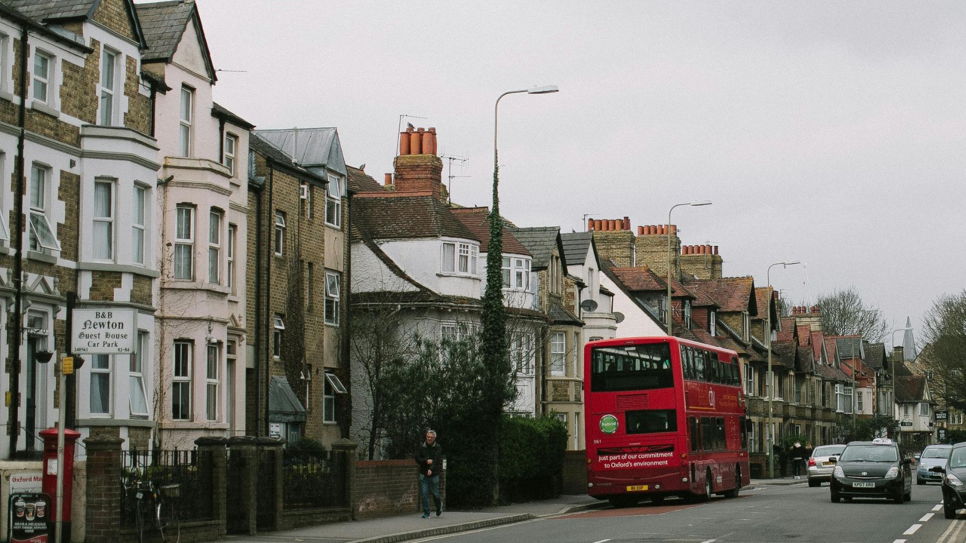 Photo of houses in the UK with a red bus in the foreground