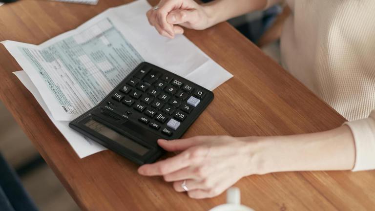 a woman's hands over a calculator and papers on a desk