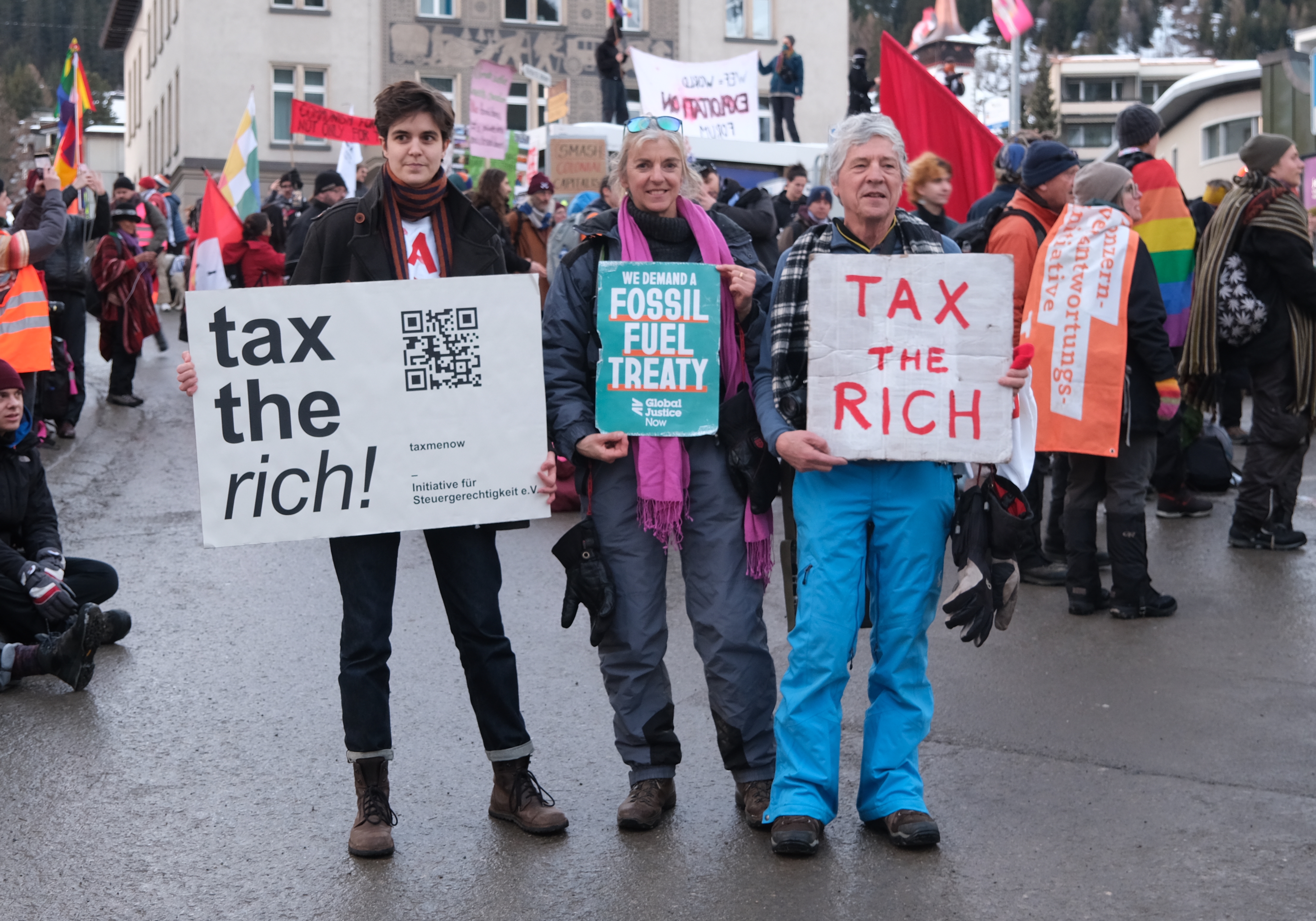 Phil White (right) and other protesters holding up signs reading "Tax the Rich"