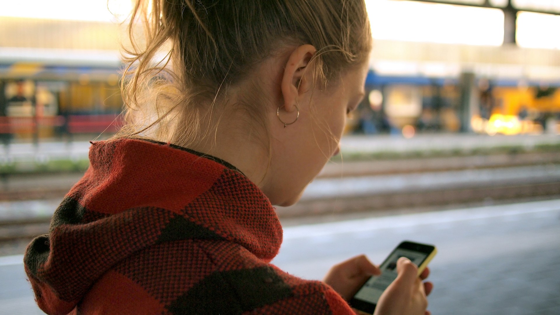 view from behind a woman's head of her holding and looking at a smartphone