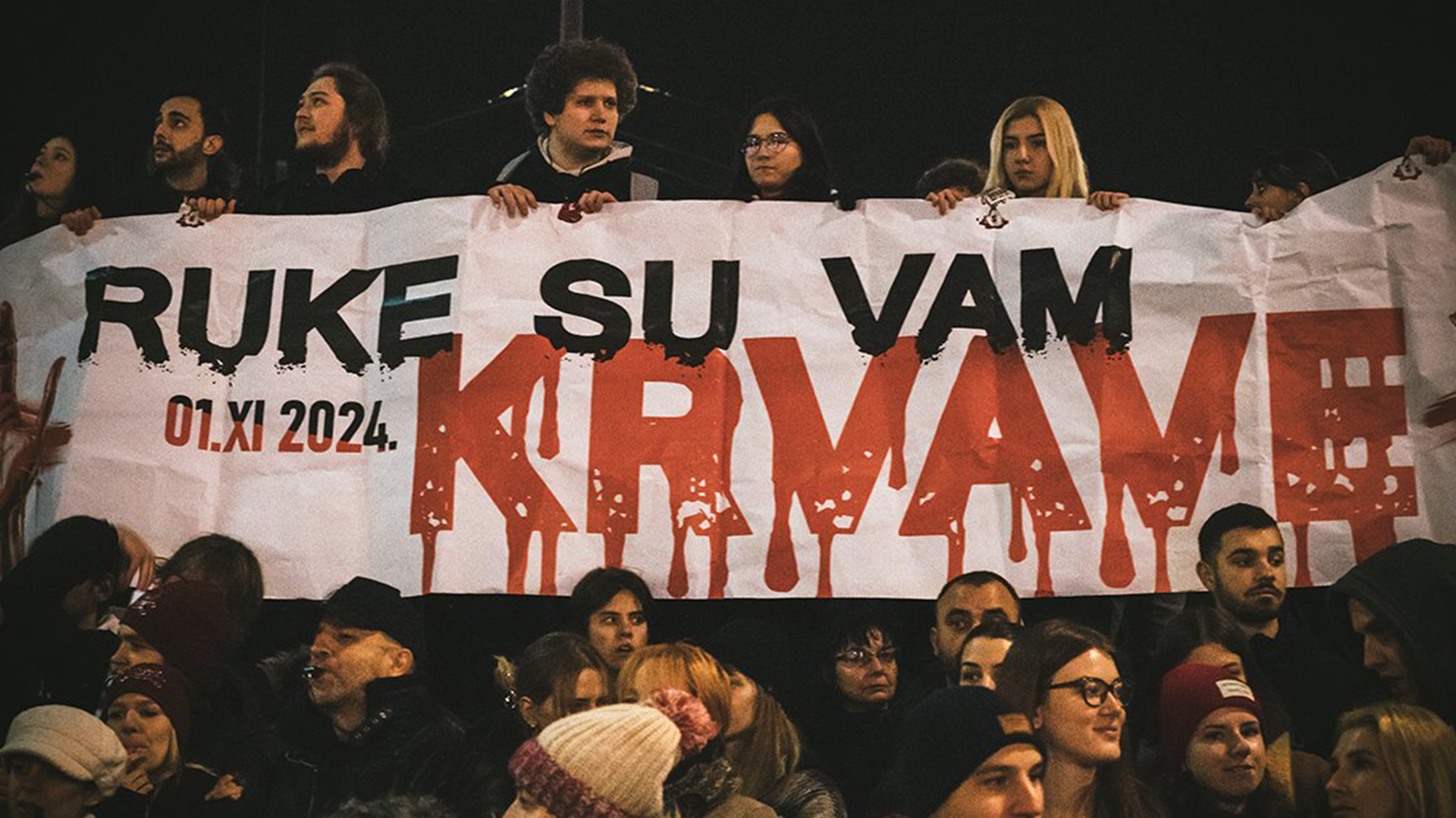 Protesters in Serbia holding up a sign which translates as 'Your hands are bloody"