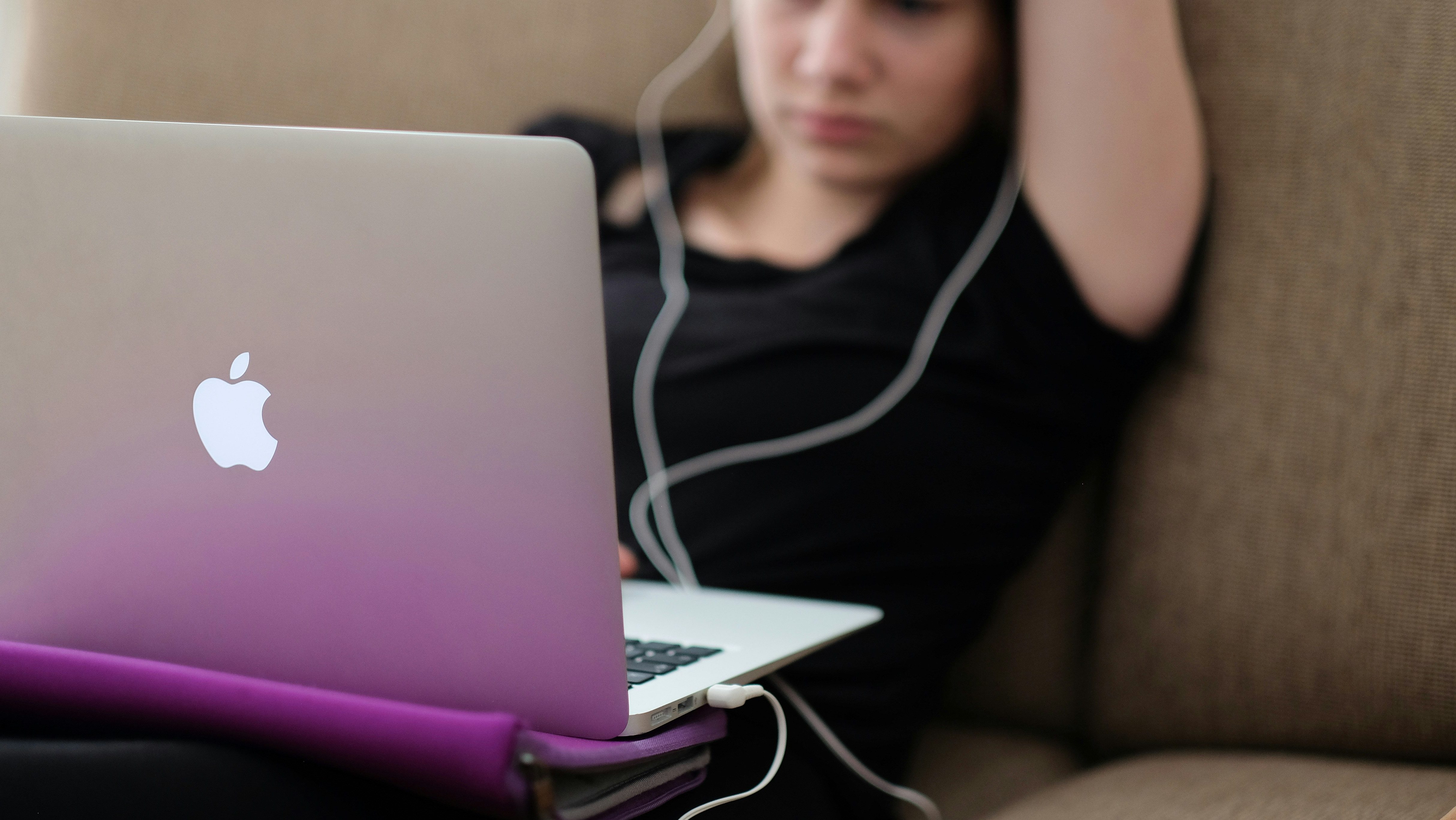 A young person slouches while working on a MacBook