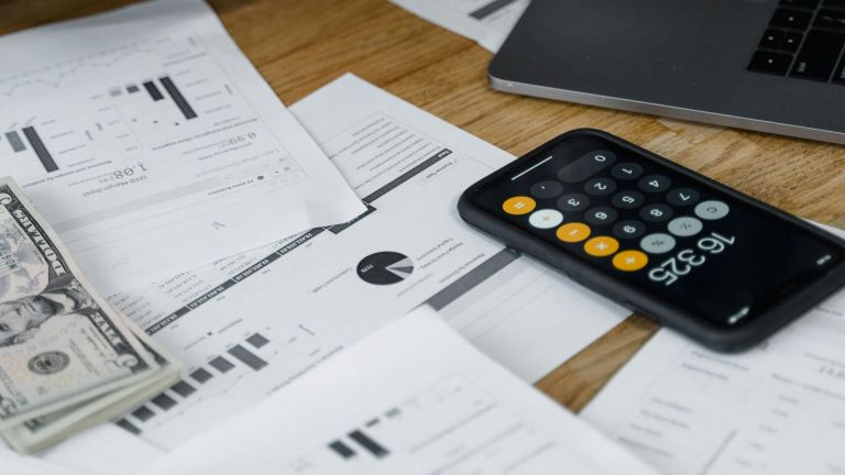 Stock image of a calculator with papers and a laptop