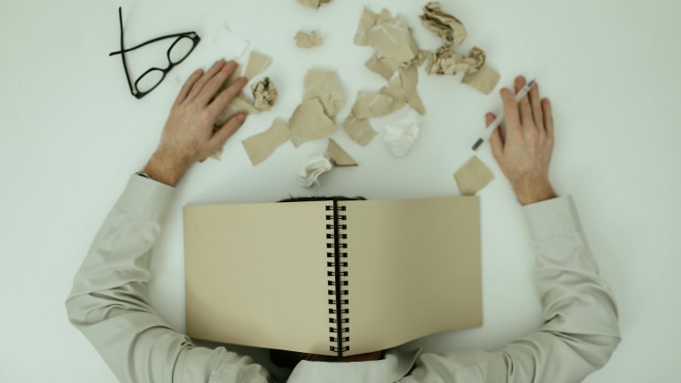 person with book on head and papers scattered around